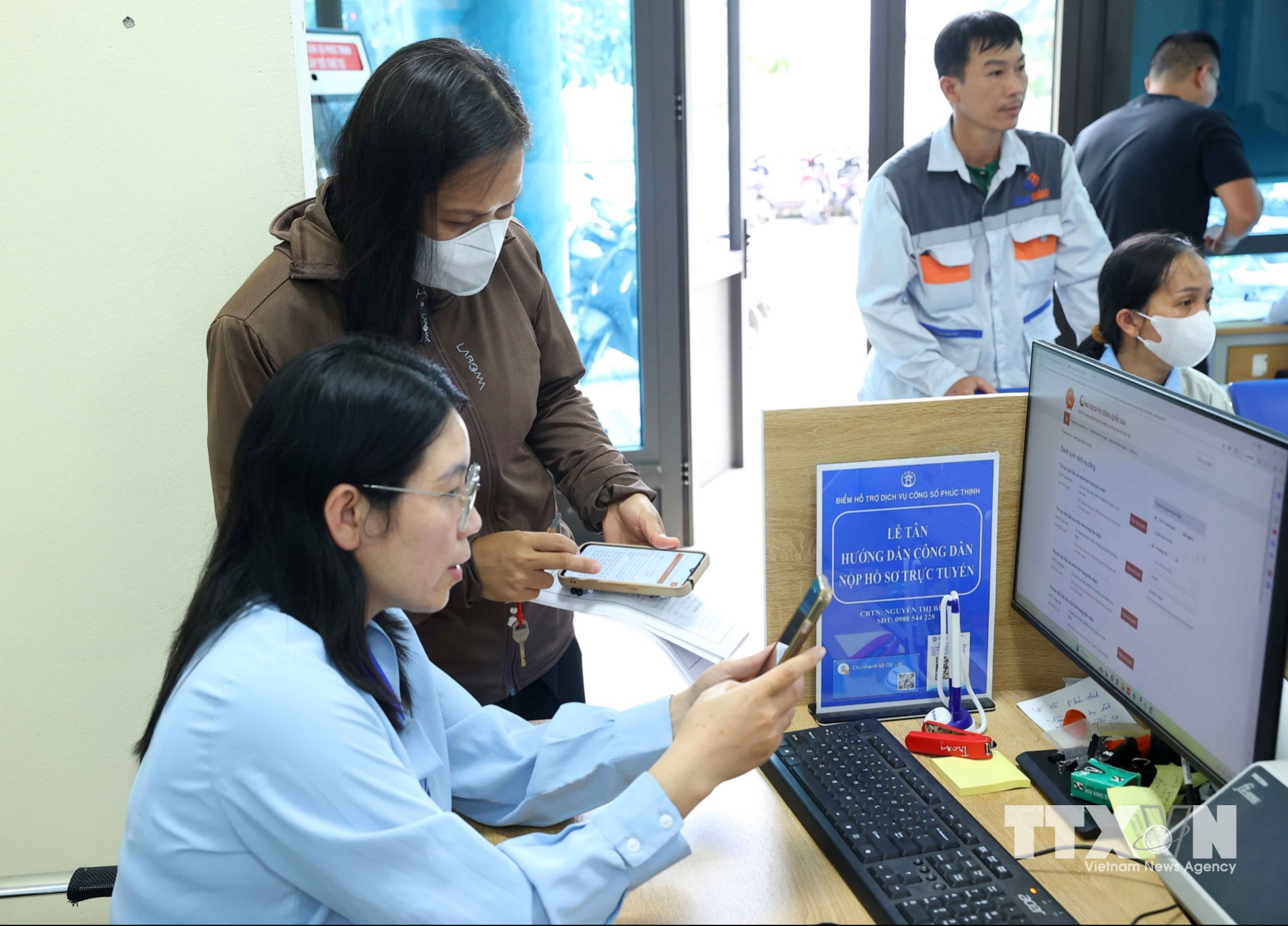 Cán bộ Điểm phục vụ hành chính công xã Phúc Thịnh tận tình hỗ trợ người dân làm thủ tục hành chính. (Ảnh: Văn Điệp/TTXVN)